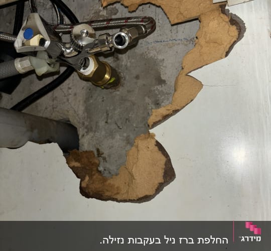 צינורות מתכת וברזים מתחת לכיור עם נזק מים